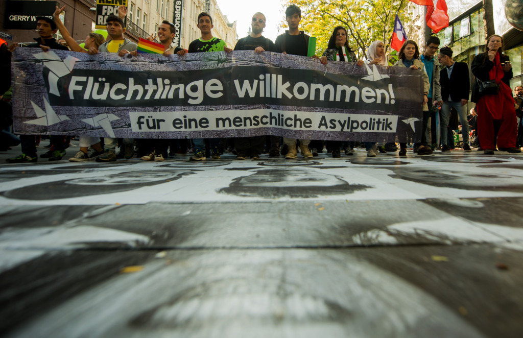 ap foto : christian bruna : people hold a banner reading refugees welcome, for a human asylum policy as they walk over portraits of refugees and volunteers during a demonstration for a change in austrian and european refugee policy in vienna, austria, saturday, oct. 3, 2015. (ap photo/christian bruna) austria migrants demonstratio automatarkiverad