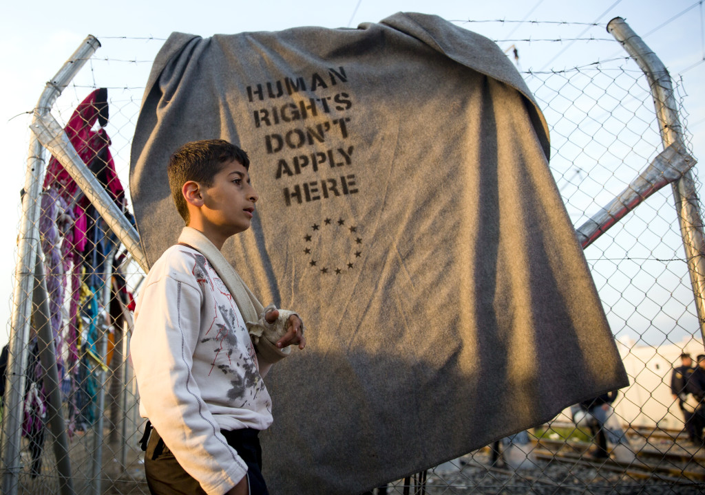 ap foto : vadim ghirda : a migrant walks past an improvised banner after news of the brussels summit agreement reached the inhabitants of the make shift refugee camp at the northern greek border point of idomeni, greece, friday, march 18, 2016. more than 46,000 people are trapped in greece, after austria and a series of balkan countries stopped letting through refugees who reach greece from turkey and want to go to europe's prosperous heartland while greece wants refugees to move from idomeni to organized shelters. (ap photo/vadim ghirda) greece migrant automatarkiverad